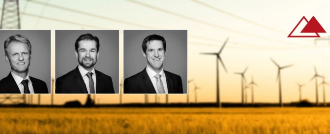 4 ENLITE Mitarbeiter mit einer Windkraftanlage im Hintergrund